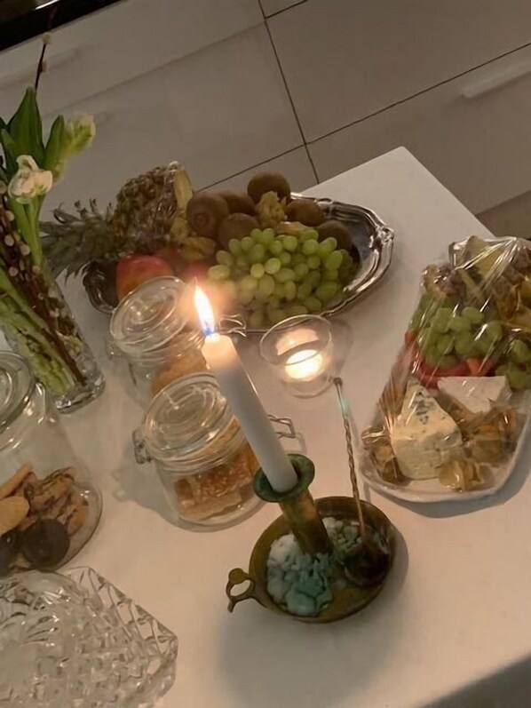 Ett bord med olika sorters mat och ett tänt ljus.