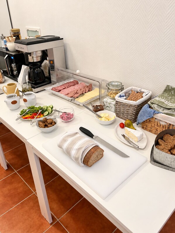 A buffet table with various food items, a coffee machine, and a knife on a white table. - Mälarö Hotell (Ekerö)