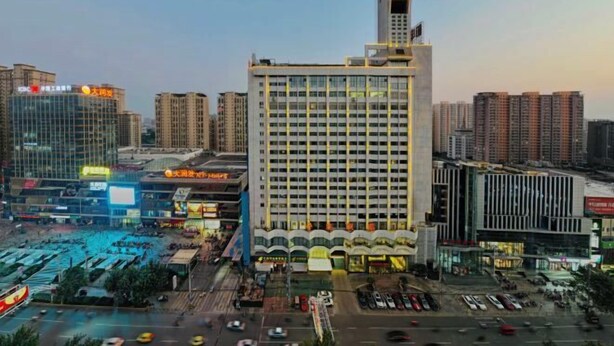 Un hotel de gran altura con una torre destacada, rodeado de otros edificios y una calle concurrida con coches y peatones.