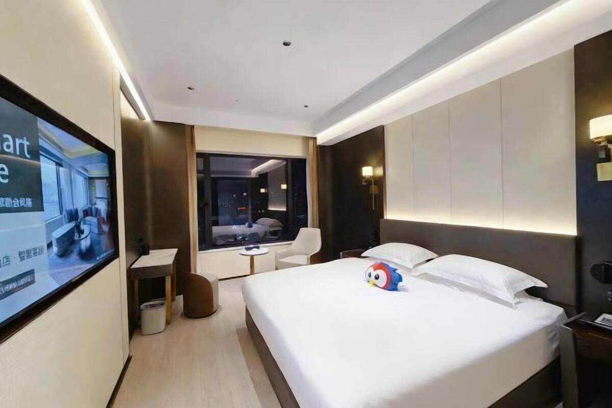 Een moderne hotelkamer met een groot bed, een bureau, een stoel en een televisiescherm.