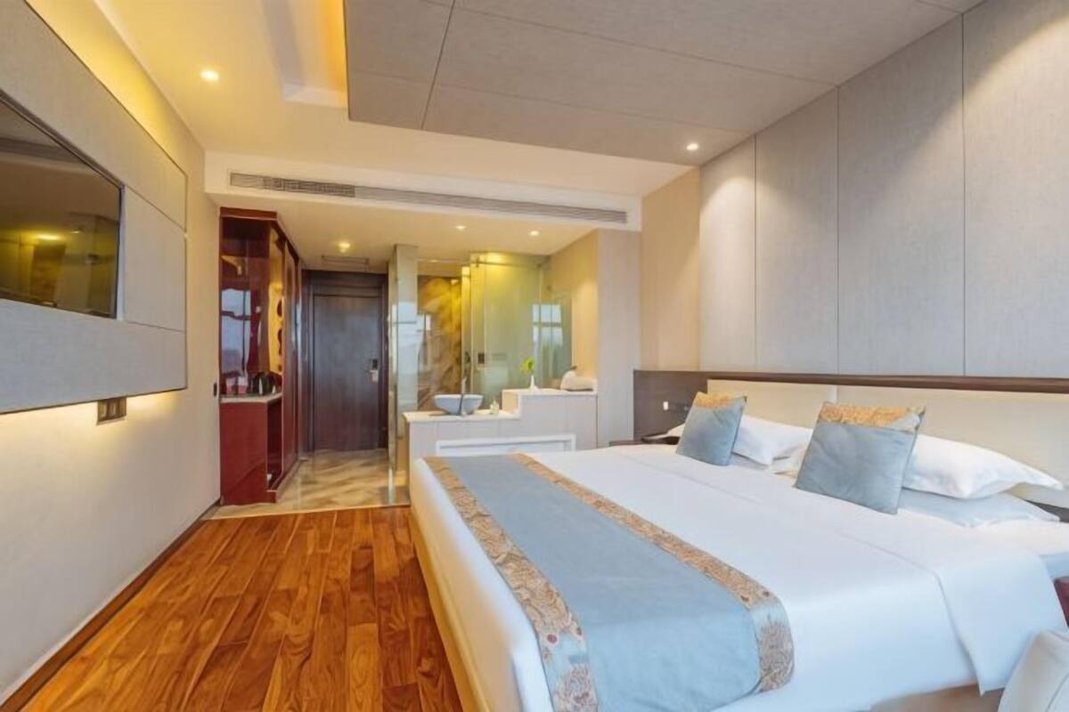 Een moderne hotelkamer met een groot bed, een inloopkast en een badkamer met spiegel en wastafel.