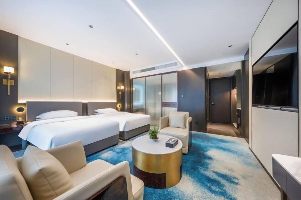 Een moderne hotelkamer met twee bedden, een bank, een bijzettafeltje en een televisie.