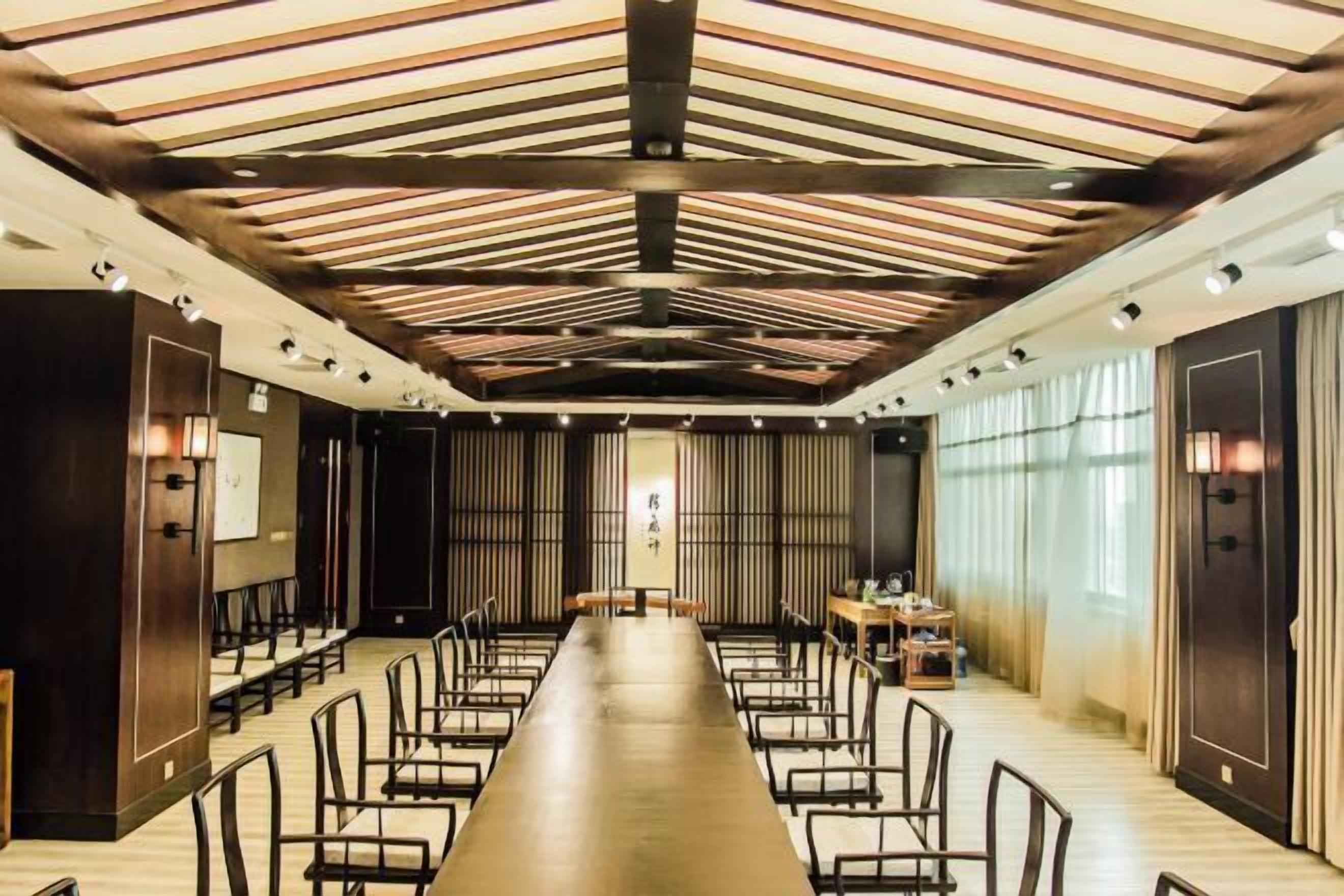 A conference room with a long table, chairs, and a wooden ceiling design.
