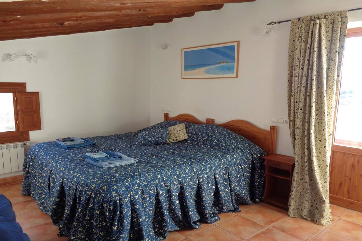 Une chambre à coucher avec un lit, une fenêtre, un radiateur et un plafond en bois.