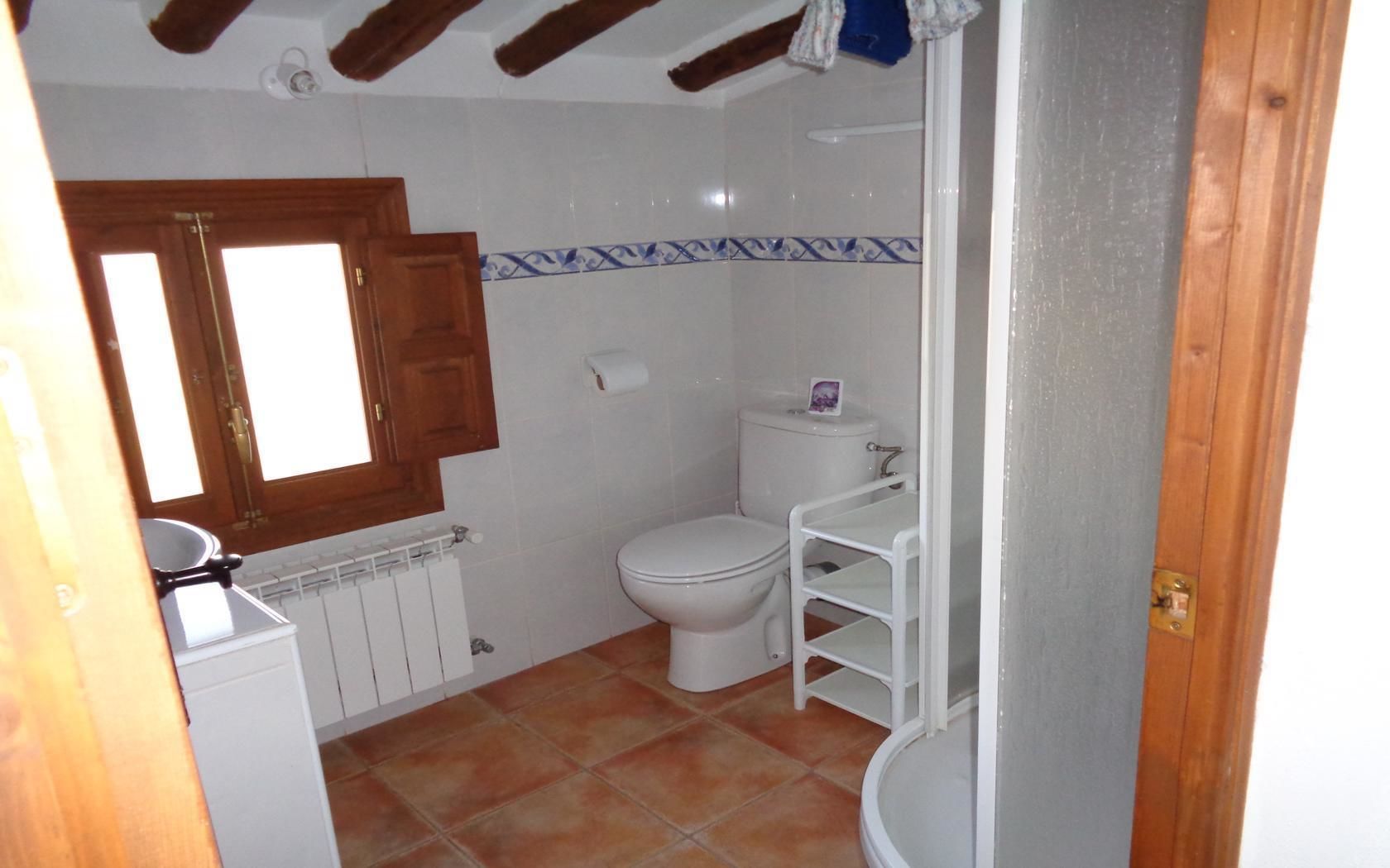 A small bathroom with a toilet, a sink, and a window.