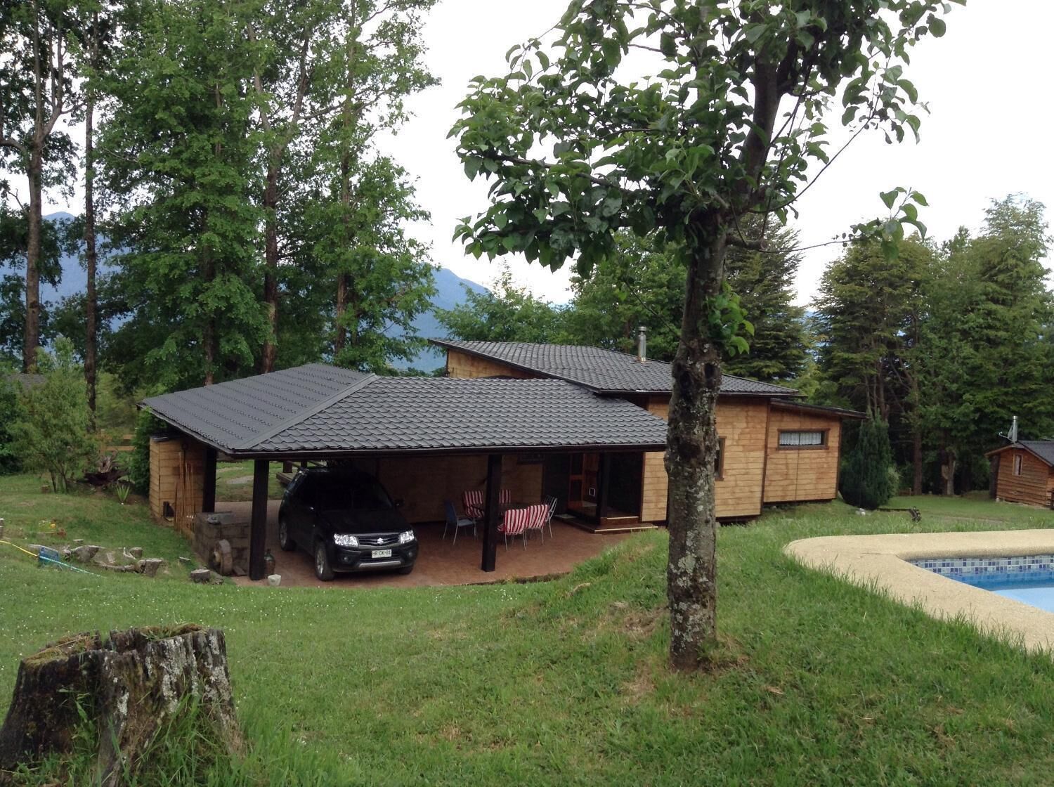 A single-story house with a covered garage, a swimming pool, and a lawn.