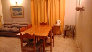 Un coin repas avec une table et des chaises en bois, un canapé et une petite table sur laquelle se trouvent une tasse et un objet décoratif.