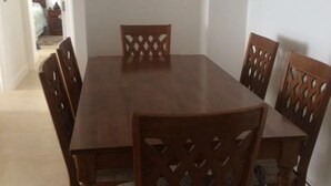 A dining area with a rectangular wooden table and six chairs with intricate back designs. - Fragata 802 (Coquimbo)
