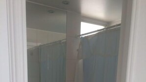 A small, compact bathroom with a toilet, a sink, and a shower area. - Fragata 802 (Coquimbo)