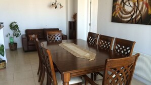 A dining area with a wooden table and chairs, a woven placemat, and a painting on the wall. - Depto 203 Fragata Condominio Playa (La Serena)