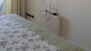 A room with a bed, a television mounted on the wall, and a radiator below it. - Depto 203 Fragata Condominio Playa (La Serena)