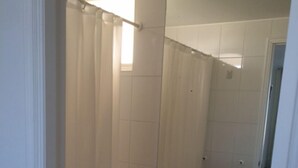 A small, compact bathroom with a toilet, a sink, and a mirror. - Depto 203 Fragata Condominio Playa (La Serena)