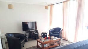 A living room with a sofa, two armchairs, a coffee table, a TV, and a sound system. - Piscina Cristalina Coral (La Serena)