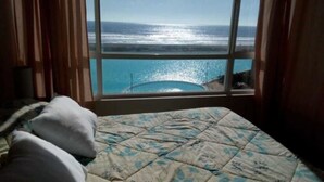 A bedroom with a bed, a window with a view of the ocean and a swimming pool. - Piscina Cristalina Coral (La Serena)