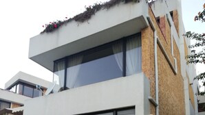 Moderni rakennus, jossa on suuret ikkunat, parveke ja pysäköintialue.