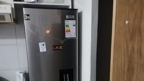 Ruostumattomasta teräksestä valmistettu jääkaappi, jossa on pakastinosa, ohjauspaneeli ja tarra, joka osoittaa energiatehokkuuden.