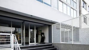 Une entrée moderne, avec un escalier noir menant à une porte en verre.