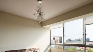 Un salon moderne avec un canapé en cuir marron, une table basse en verre et une grande fenêtre donnant sur le paysage urbain.