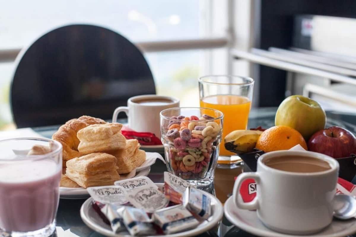 A breakfast setting with pastries, a glass of orange juice, a cup of coffee, and a bowl of cereal.