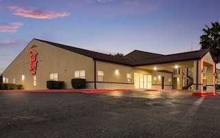 Un hotel Red Roof Inn con techo plano, entrada cubierta y estacionamiento.