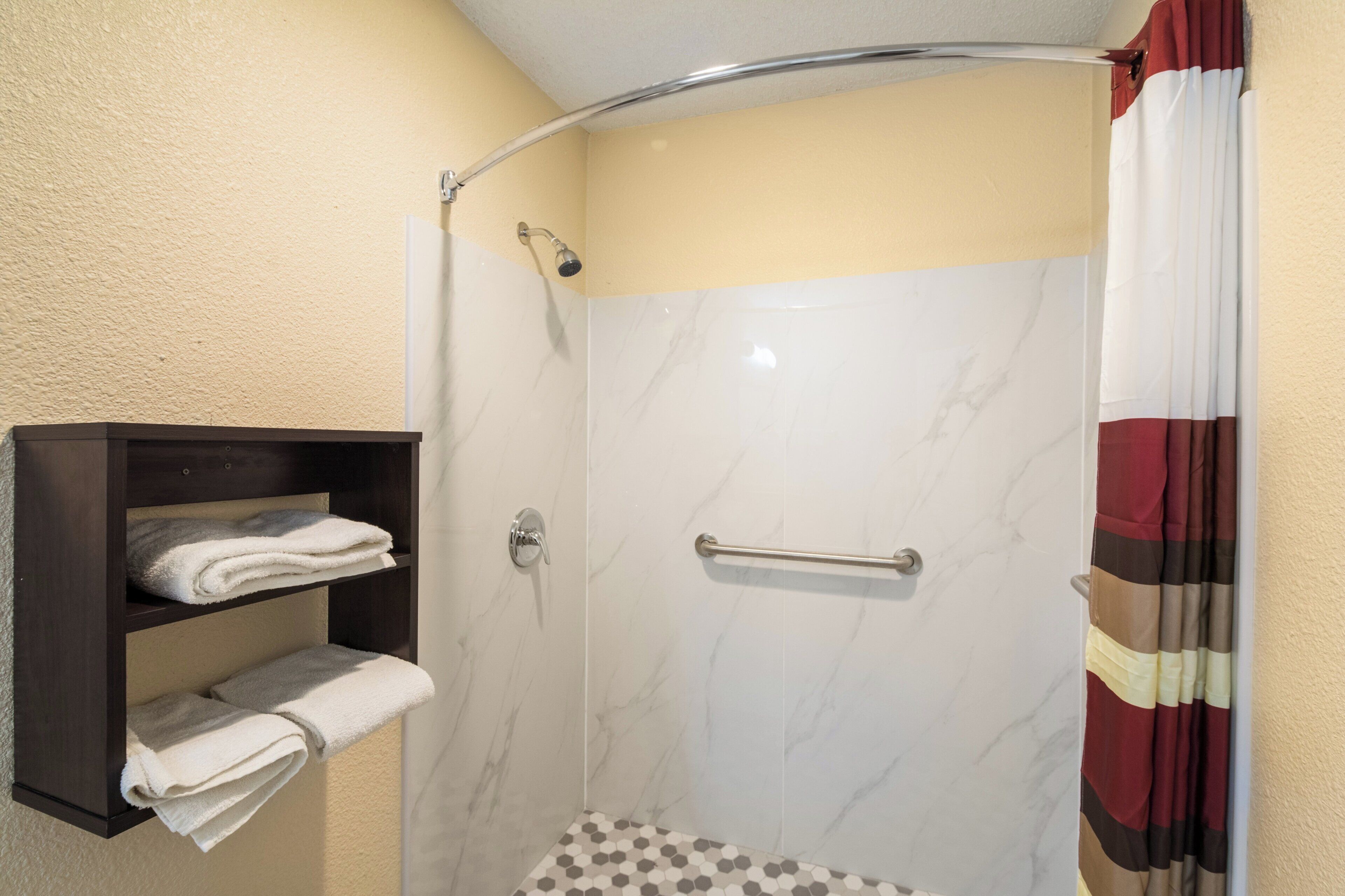 A shower with a glass door, a towel rack, and a shower curtain.