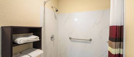 A shower with a glass door, a towel rack, and a shower curtain.