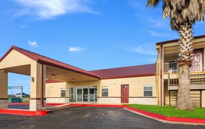 A two-story building with a covered entrance, a palm tree, and a red curb. - Red Roof Inn Temple (Temple)