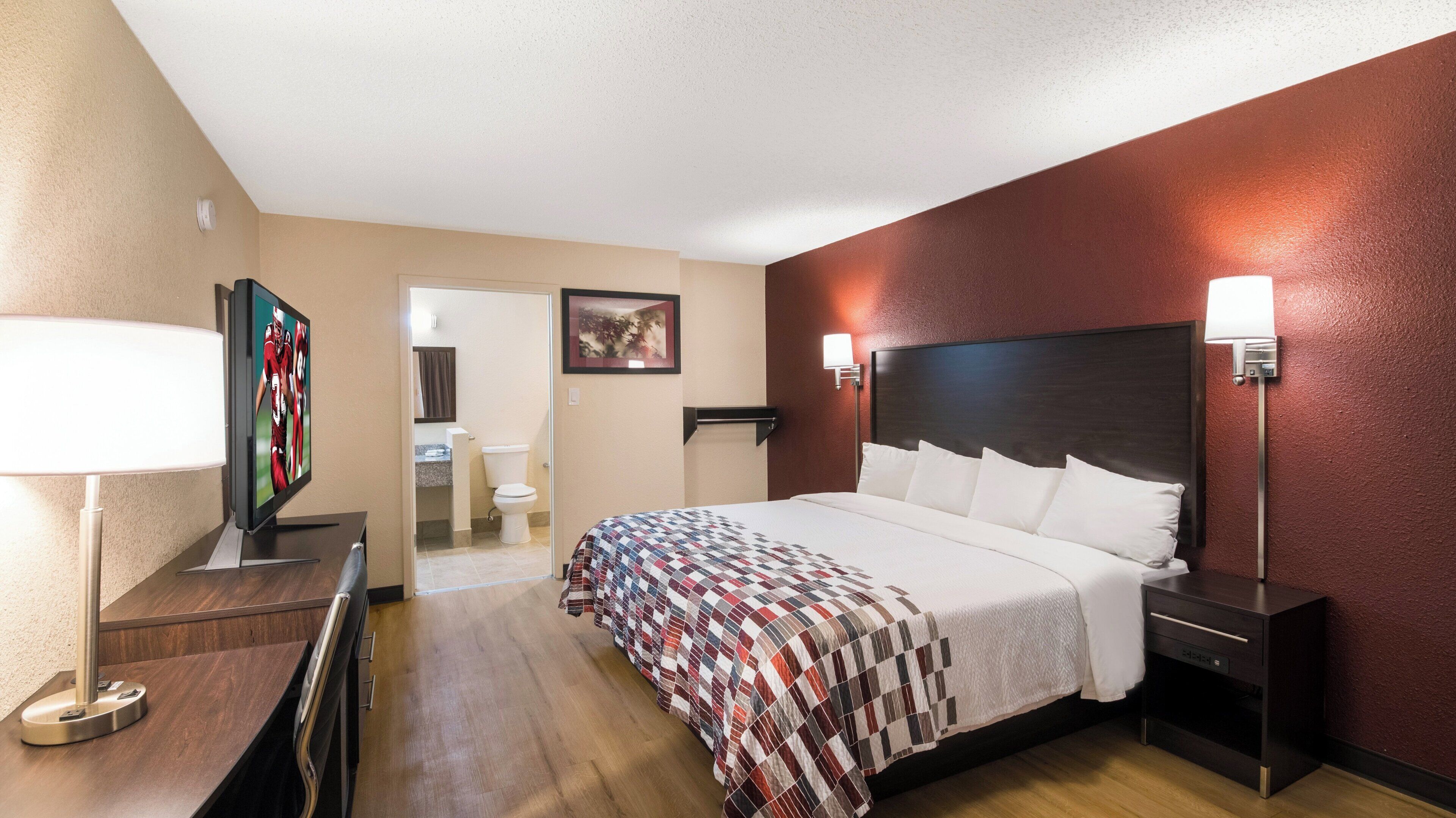 Une chambre d’hôtel avec un lit, des lampes de chevet, une télévision et vue sur la salle de bain.