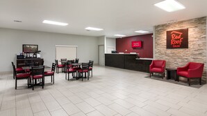 A hotel reception area with a Red Roof Inn sign, a coffee machine, and seating arrangements. - Red Roof Inn Temple (Temple)