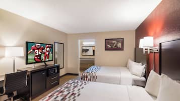 A hotel room with a television, a desk, a chair, two beds, a lamp, and a painting on the wall.
