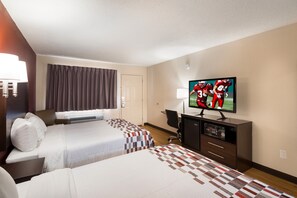 Habitación de hotel con dos camas, televisión, escritorio y una silla.