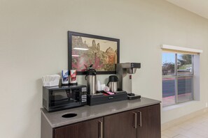 A coffee station with a coffee maker, a microwave, and a coffee creamer dispenser.