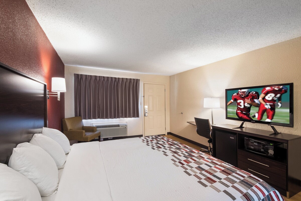 A hotel room with a bed, a TV, a desk, and a chair.
