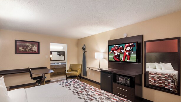 A hotel room with a bed, a desk, a chair, a television, and a mirror. - Red Roof Inn Temple (Temple)