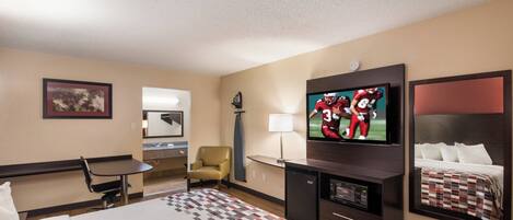 A hotel room with a bed, a desk, a chair, a television, and a mirror.