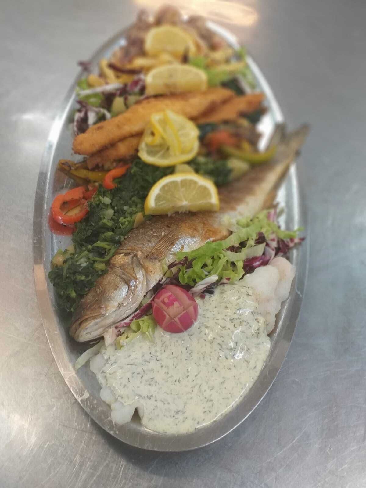 En anretning med fisk, grøntsager og en cremet sauce.