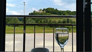 A table with a cup and a glass, a balcony with a view of a castle, and a clear sky. - Hotel Amarilis (Netretic)