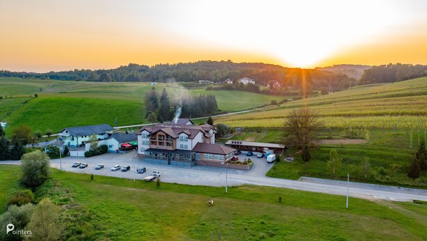 A hotel with multiple buildings, a parking area, and a view of the surrounding countryside. - Hotel Amarilis (Netretic)