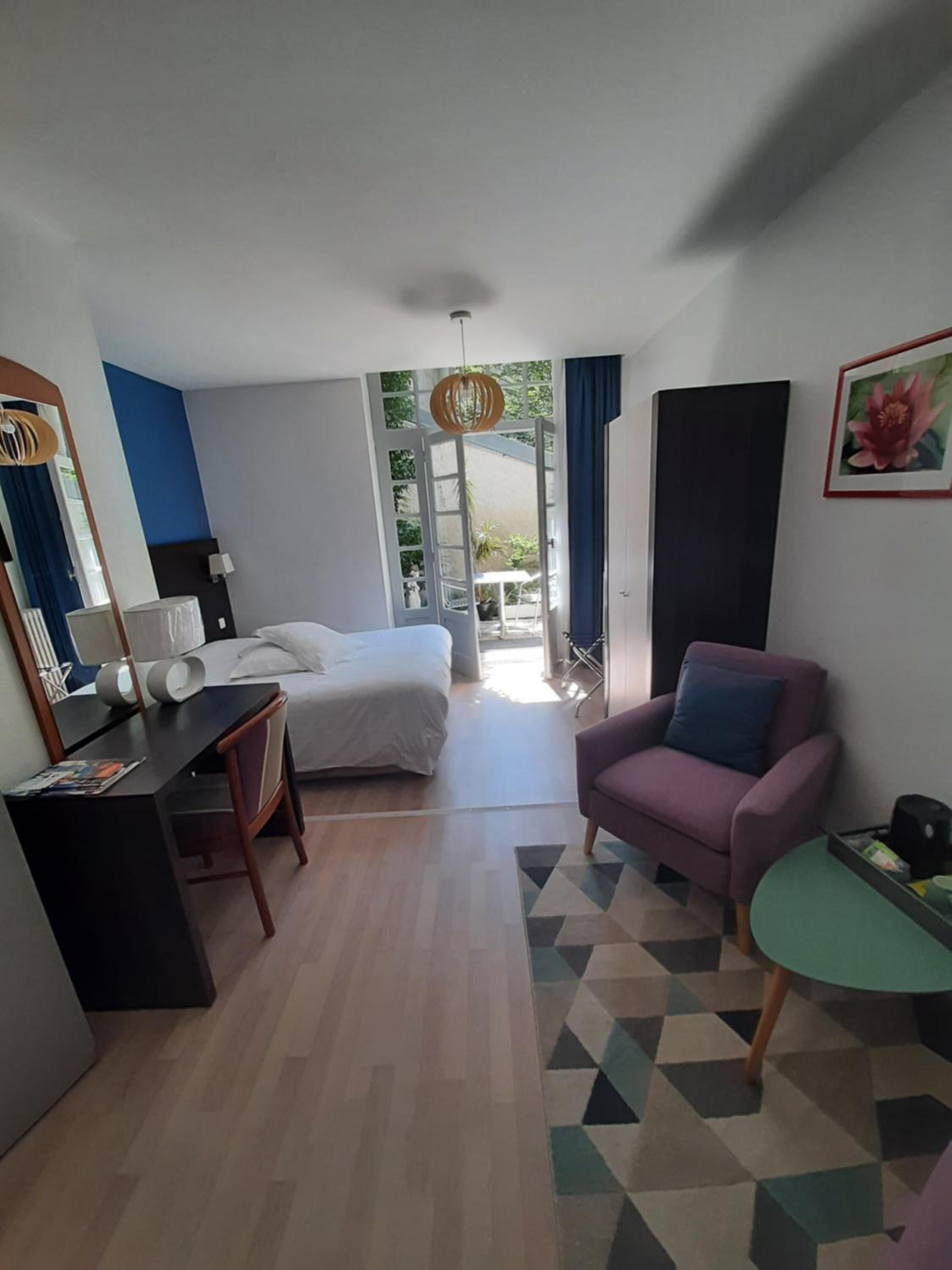 Een hotelkamer met een bed, bureau, stoel en een klein tafeltje met een groene blad.