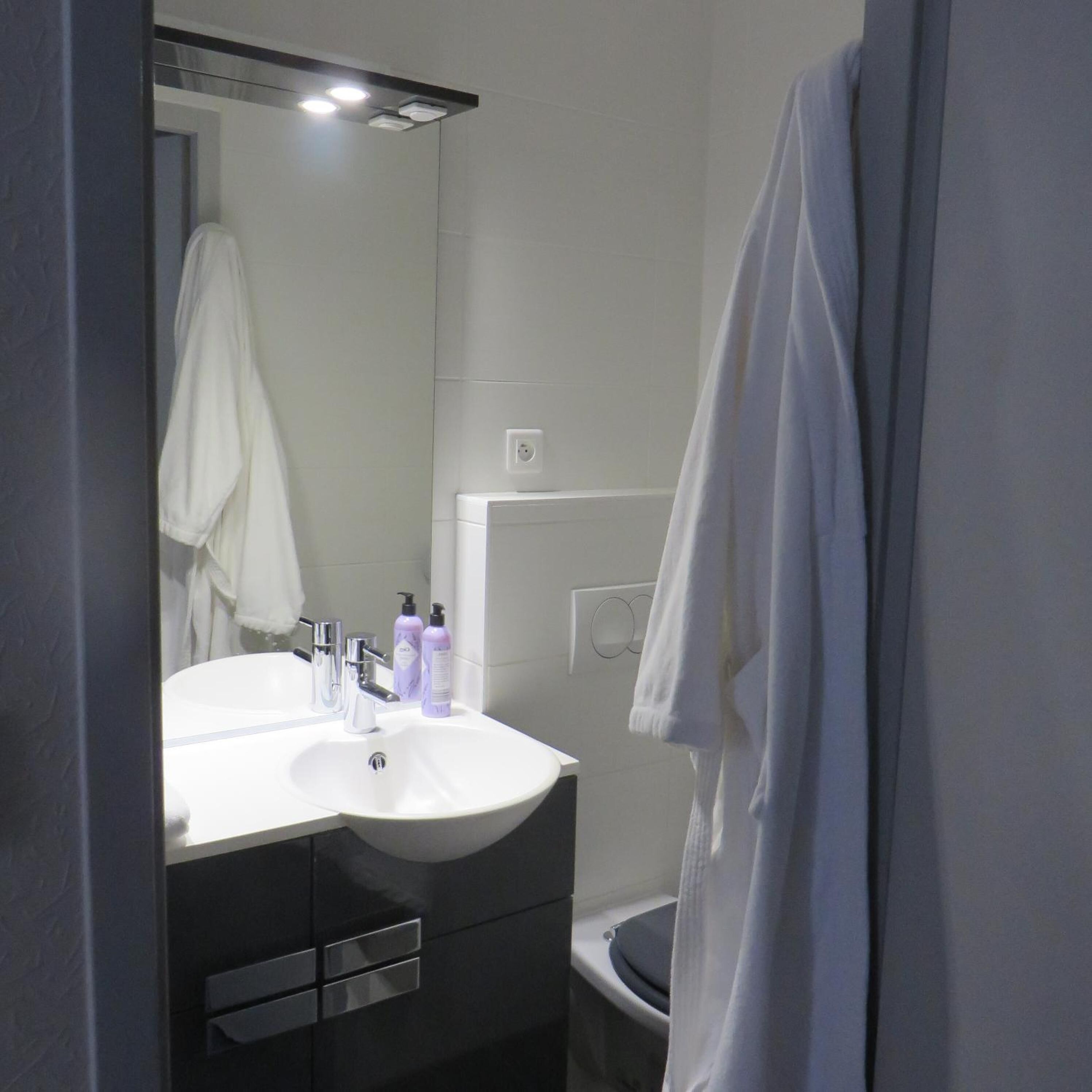 A bathroom with a white sink, mirror, and a towel hanging on the wall.