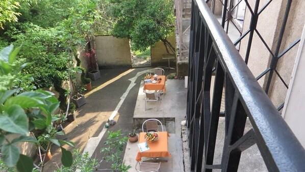 A courtyard with two tables and chairs, surrounded by potted plants and a stone wall. - Hotel Regina (Besancon)
