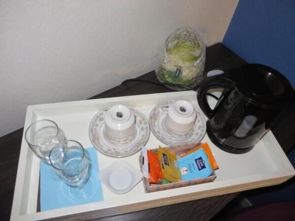 A tray with a glass, two water filters, a packet of snacks, and a black coffee maker.