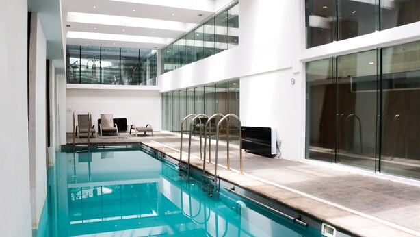 An indoor swimming pool with clear water, surrounded by glass walls and a modern interior design. - Fuente Mayor Reñaca (Vina del Mar)