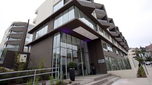 A modern building with a glass facade, multiple balconies, and a sign indicating it is a hotel. - Fuente Mayor Reñaca (Vina del Mar)