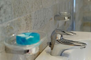 A bathroom with a chrome faucet, a soap dish, and a marble wall. - Unterbergerhof (Val di Vizze)