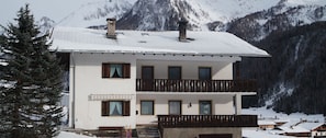 A two-story building with a balcony, surrounded by snow-covered mountains. - Unterbergerhof (Val di Vizze)