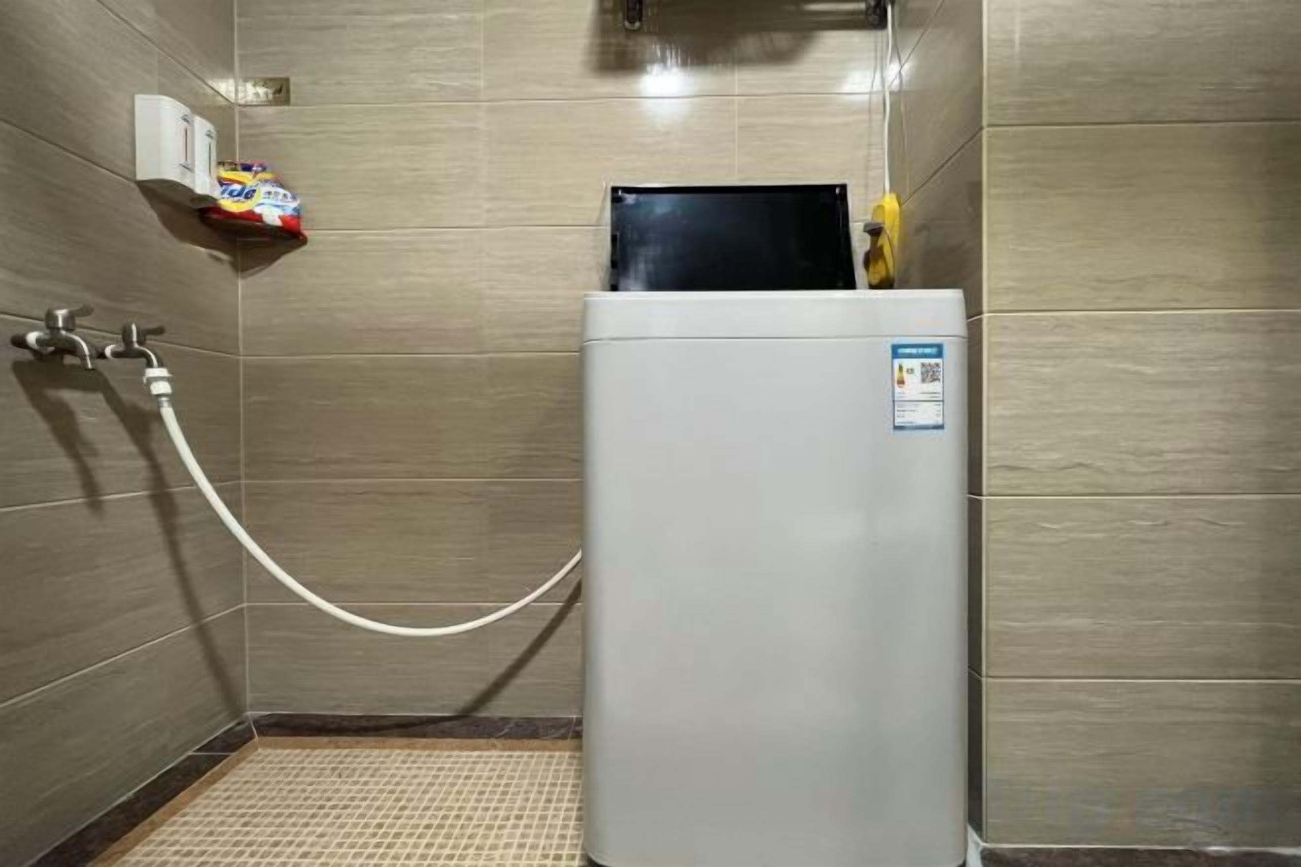 Un baño moderno y compacto con lavadora integrada, dispensador de toallas y zona de ducha.