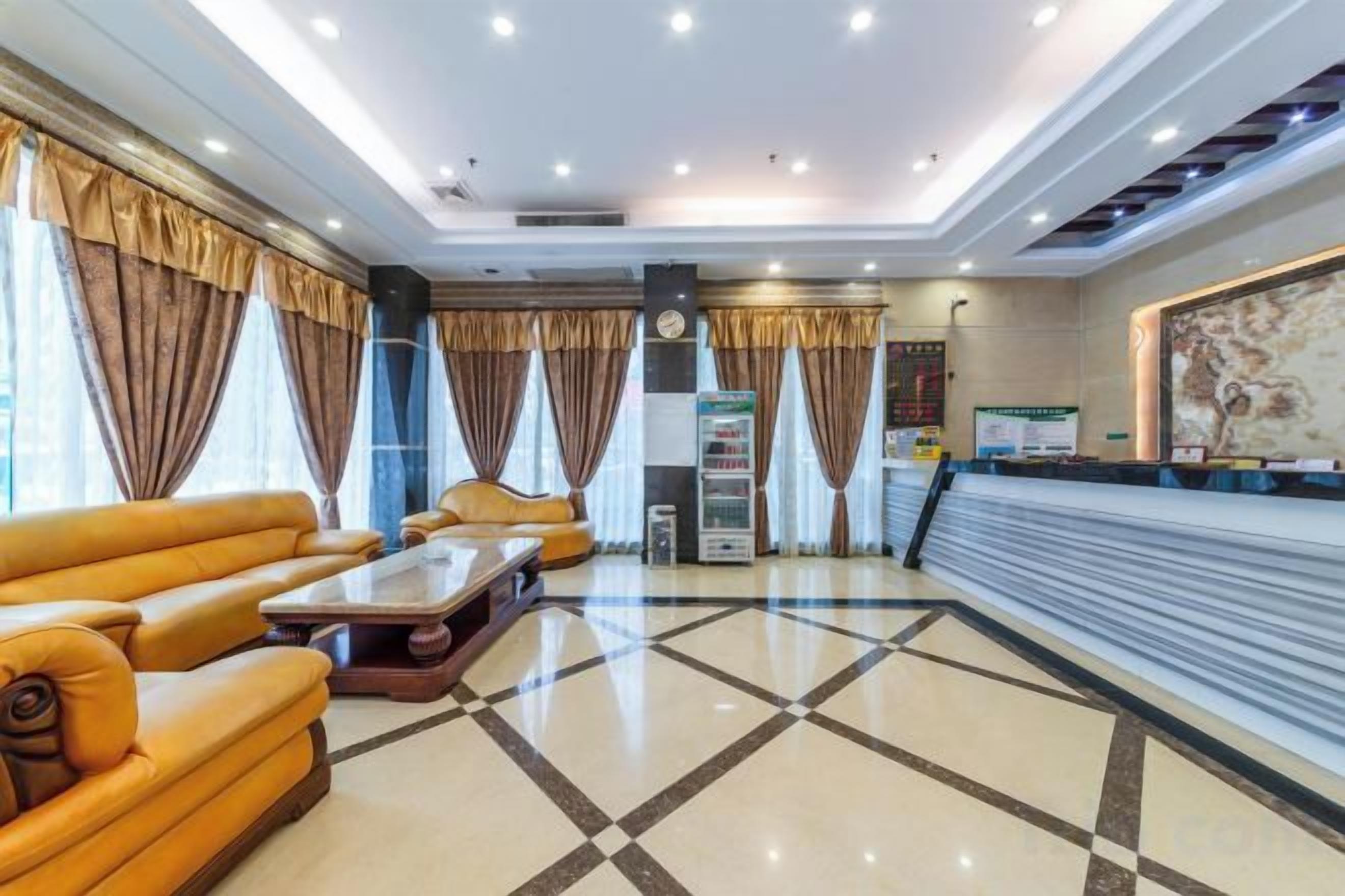 Un hall de hotel con mostrador de recepción, zona de estar con sofás y suelo de baldosas.