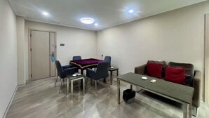 A room with a pool table, a sofa with red cushions, a coffee table, and a door. - Kaiping Fujing Hotel (Kaiping)