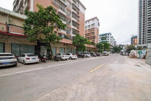 A street with parked cars, buildings, and a tree. - Kaiping Fujing Hotel (Kaiping)